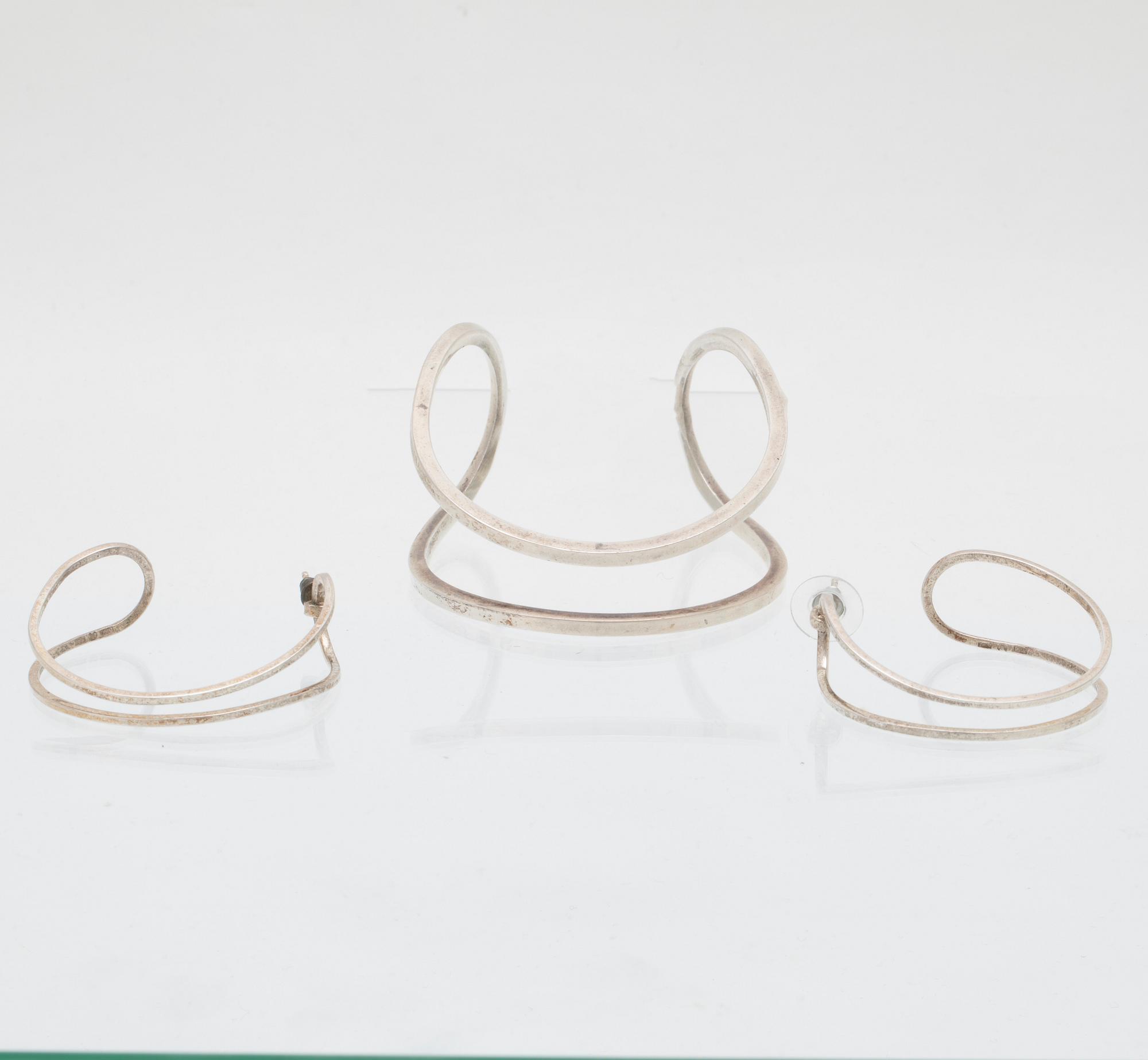 Efva Attling, stelt armband "Loop cuff" samt örhängen av silver.