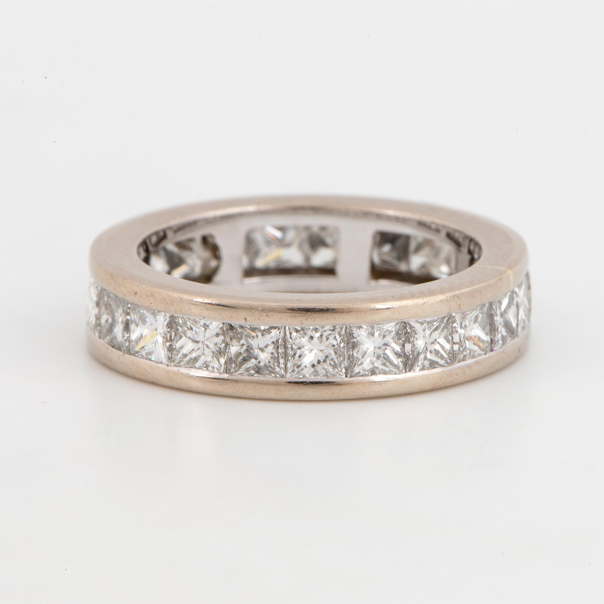 An 18K white gold eternity ring set with princess-cut diamonds.