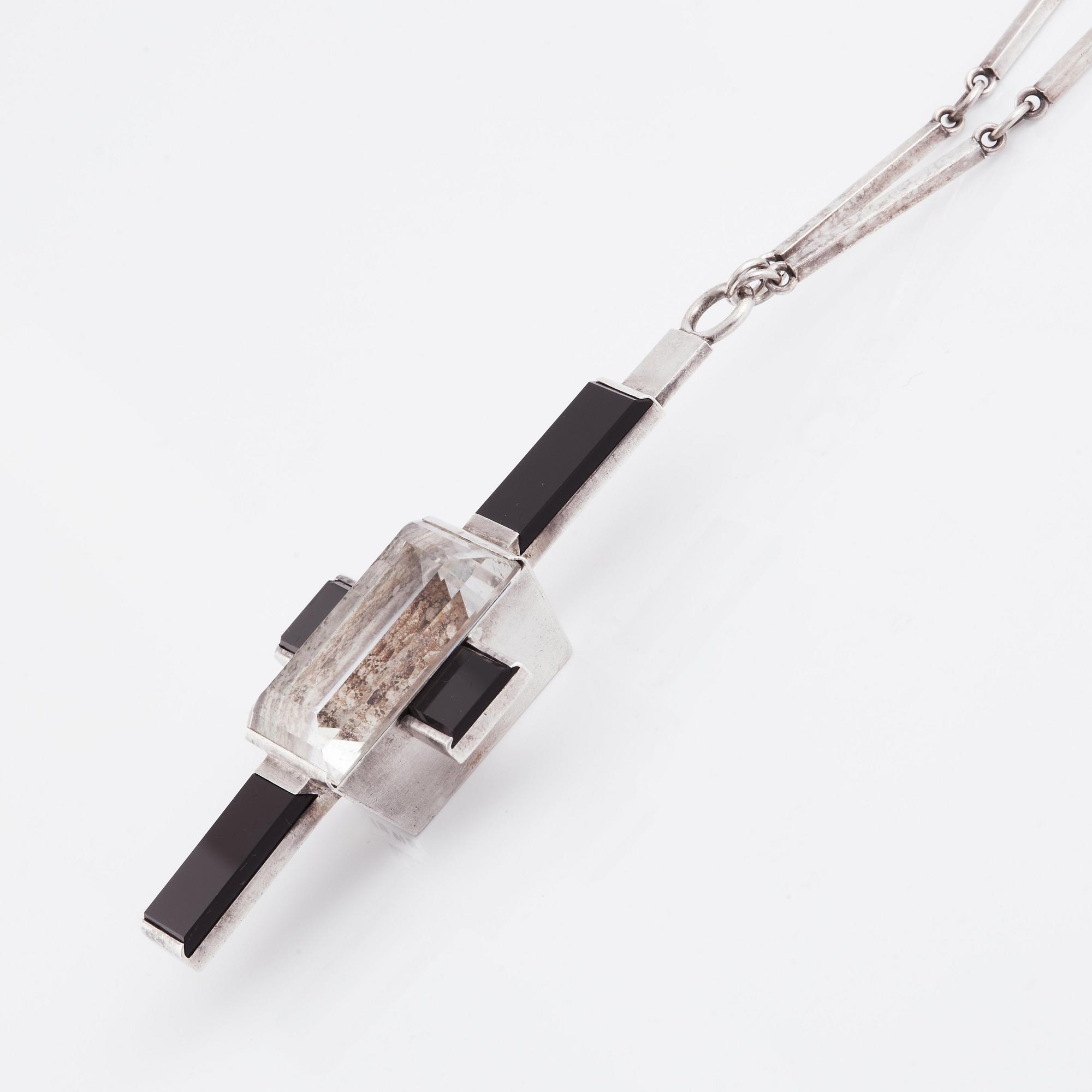 Wiwen Nilsson, hängsmycke i form av ett kors i sterlingsilver med fasettslipad bergkristall och onyx, Lund 1938.