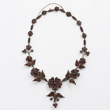 Garniture, necklace/bracelet and earrings in silver with garnets in the form of floral motifs, around the turn of the 20th century.