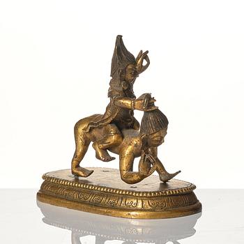 A small gilt bronze figure wrathful deity riding on a corpse, Tibeto-Chinese, 18th Century.