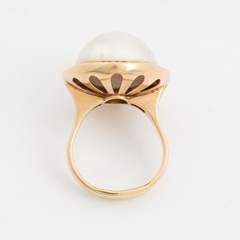 A 14 k gold ring set with a half pearl and round brilliant-cut diamonds.