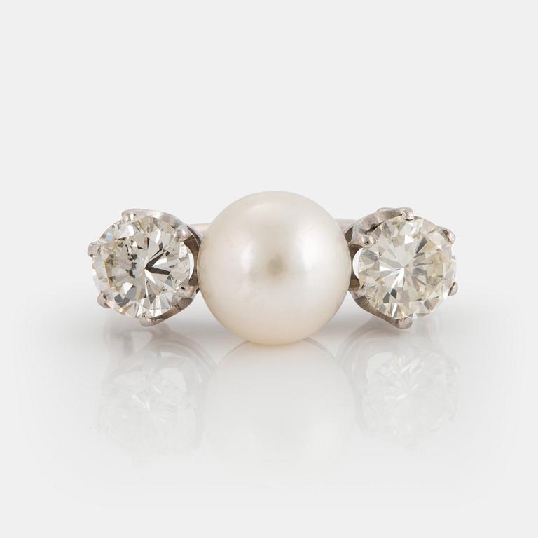 An 18K white gold ring set with a cultured pearl and two round brilliant-cut diamonds.