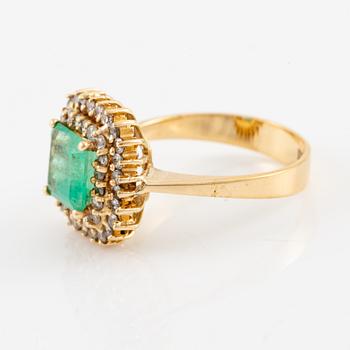 Ring in 18K gold set with a faceted emerald and round brilliant-cut diamonds.