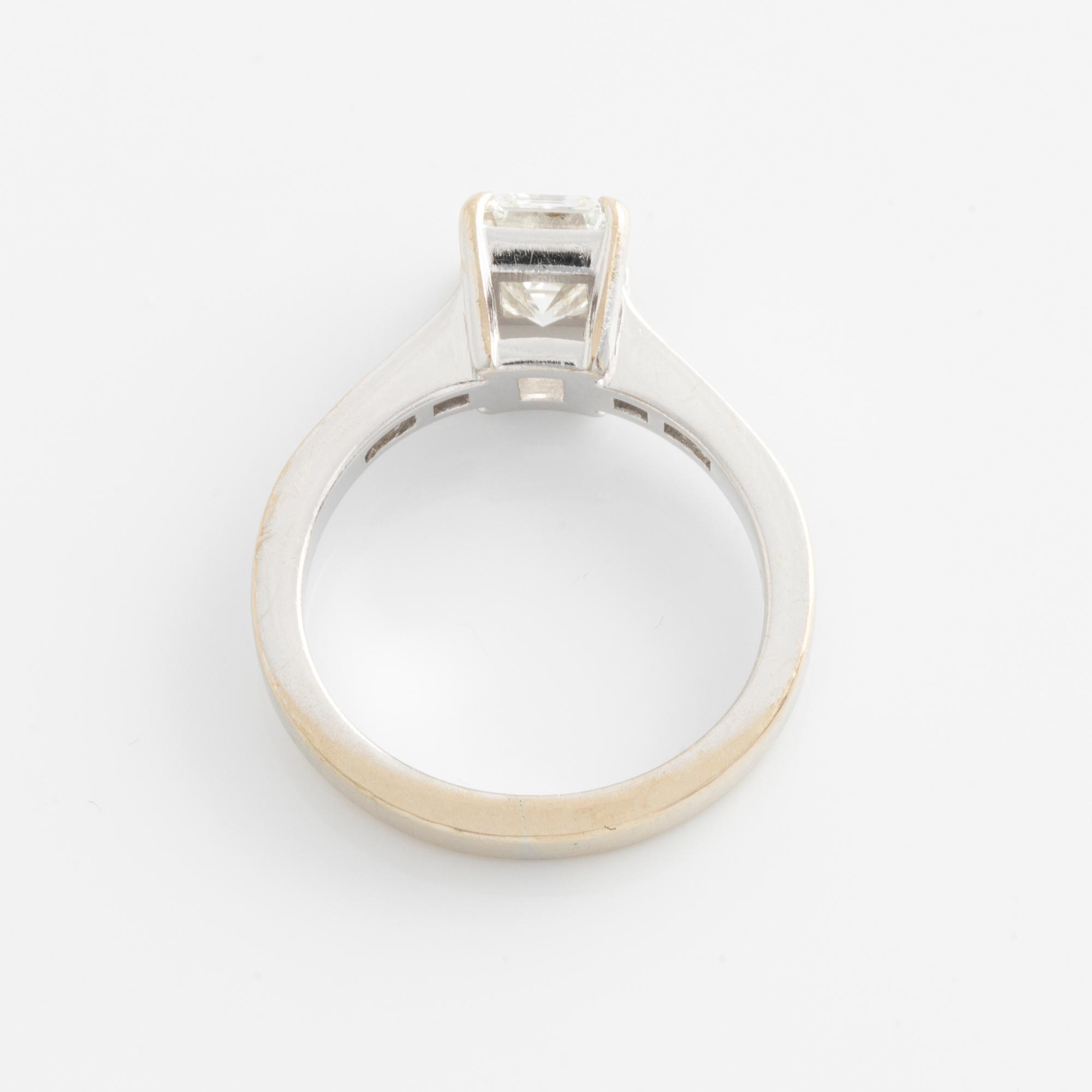 An 18K white gold ring set with an emerald-cut diamond.