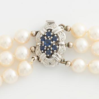 Necklace, three-stranded with cultured pearls, clasp in white gold with sapphires and small diamonds.