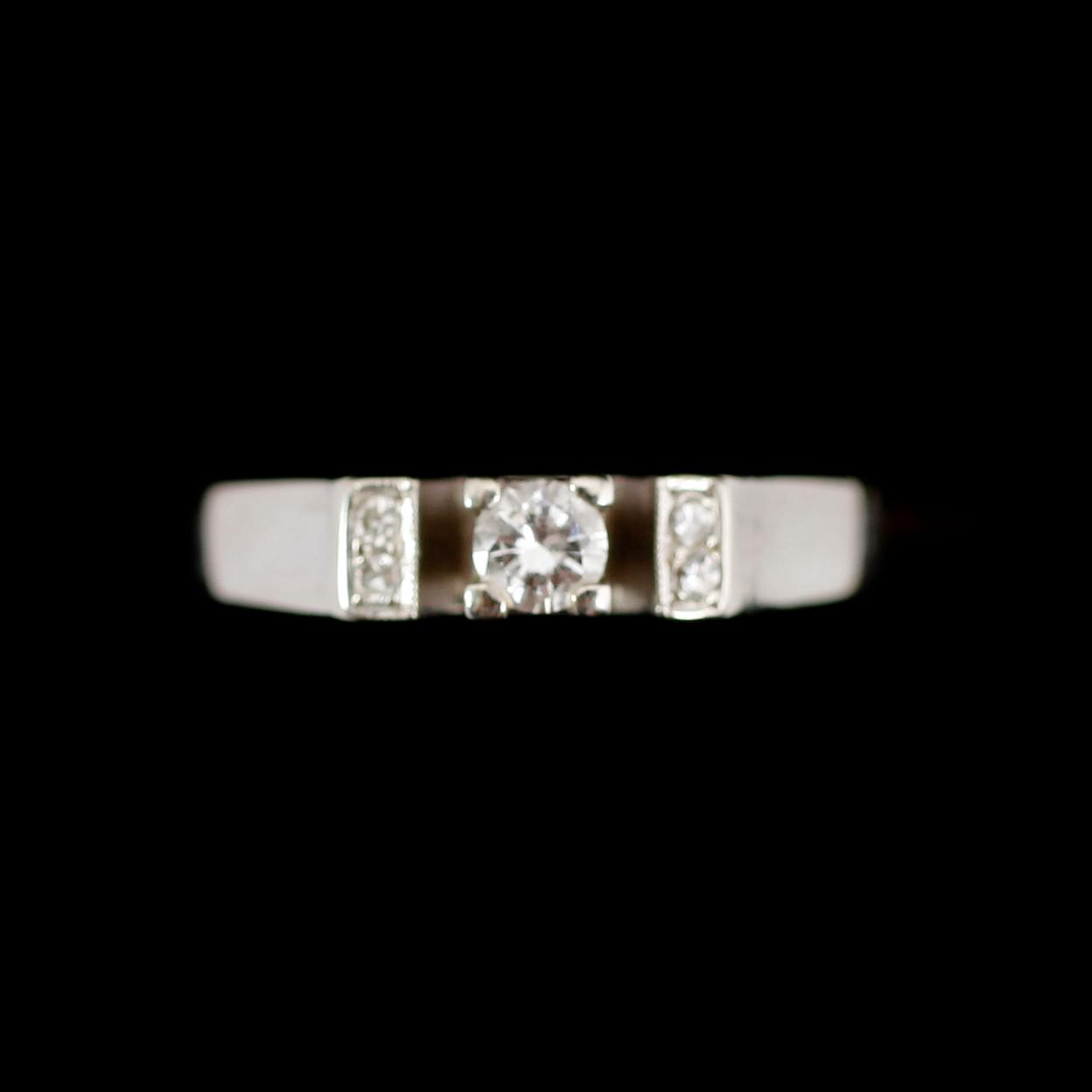 RING, 18 k vitguld, med en större och 4 mindre briljanter, 0.14 ct enligt gravyr. Total vikt ca 3 gram.