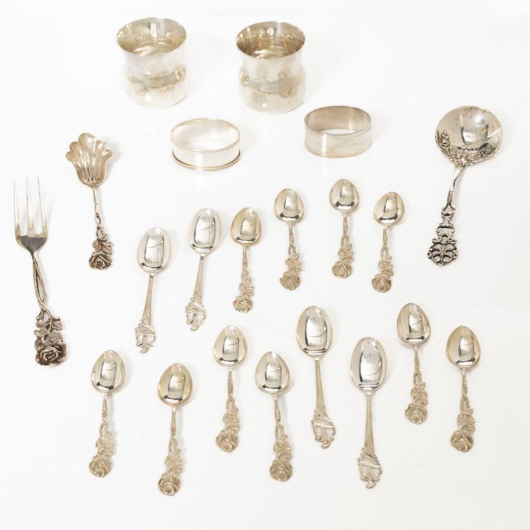 A pair of beakers, two napkin rings, and 17 pieces of cutlery, silver.