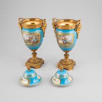 A pair of pordelain and gilt brass urns in teh style of Sevres, 20th Century.