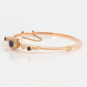 An 18K gold bangle set with faceted sapphires and old-cut diamonds.