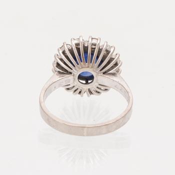 An 18K white gold ring set with a cabochon cut sapphire and round brilliant cut diamonds.