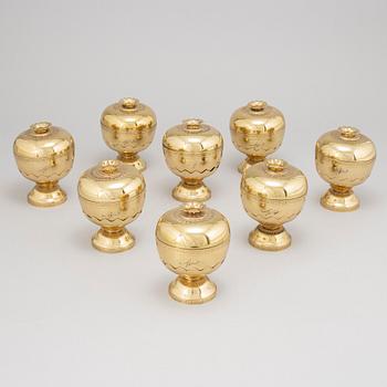 A set of eight polished brass pomme granate shaped jars with covers on stands, Marked Siam, Amfar Co.