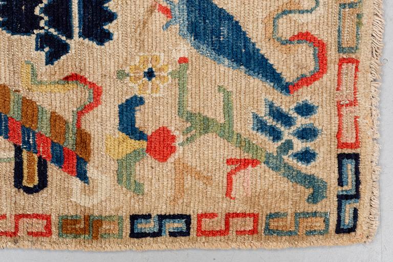 A rug, antique Tibet, ca 71 x 57,5-59 cm (as well as 1,5 cm flat weave at one end).