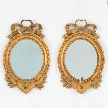 A Gustavian one-branch giltwood girandole mirror (with an associated copy), Stockholm, late 18th century.