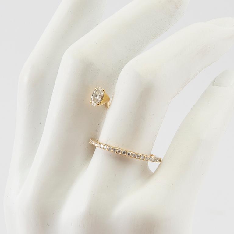 An 18K gold ring set with an oval cut and round brilliant cut diamonds by LWL Jewelry.