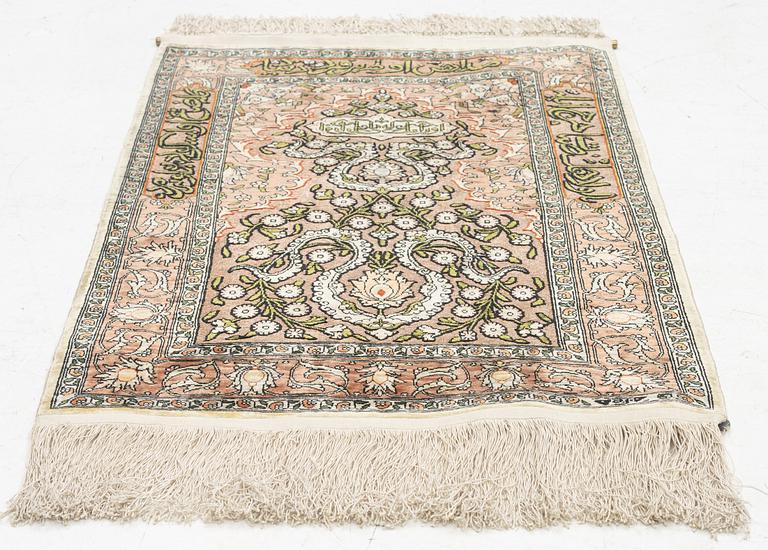 A silk Hereke rug, c. 77 x 53 cm.