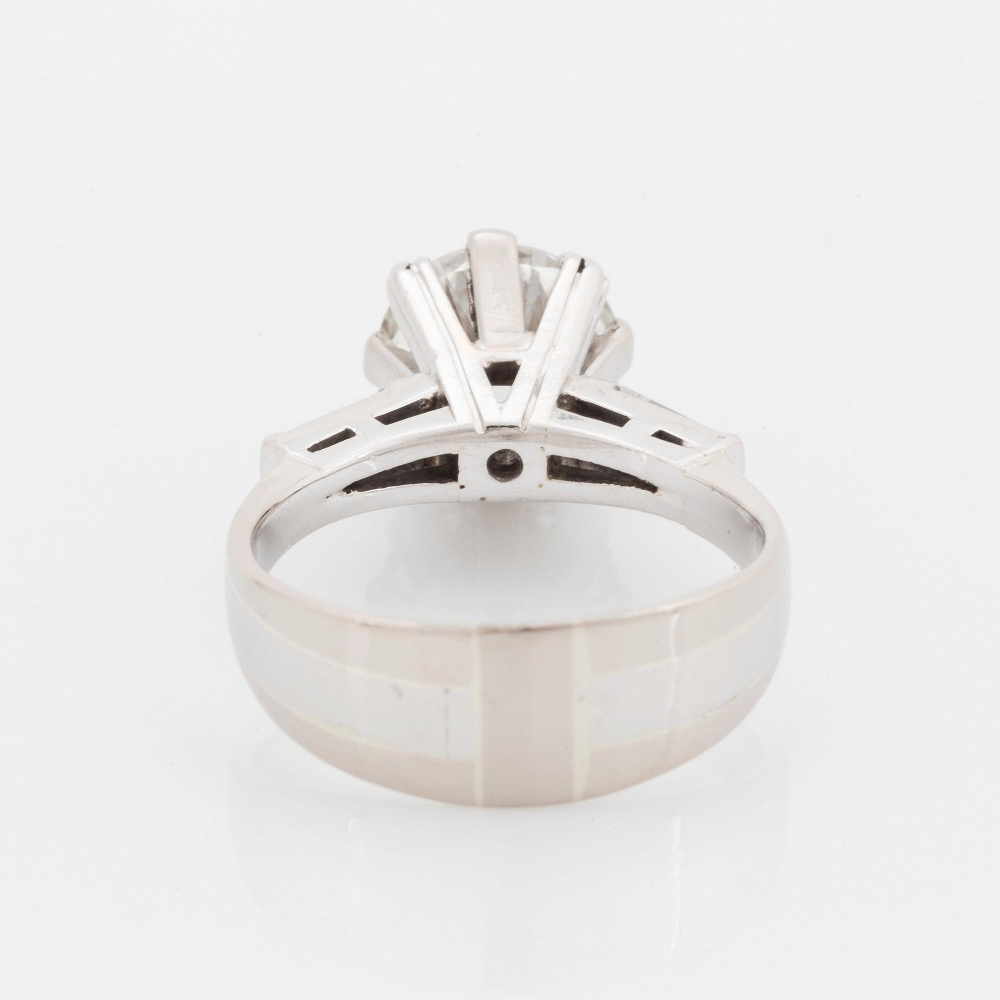 An 18K white gold ring set with a round brilliant-cut diamond and two tapered baguette-cut diamonds.
