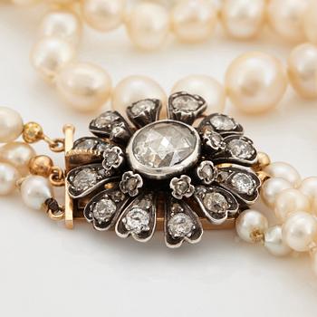 A three strand cultured pearl necklace with a clasp in 18K gold and silver set with rose- and old-cut diamonds.