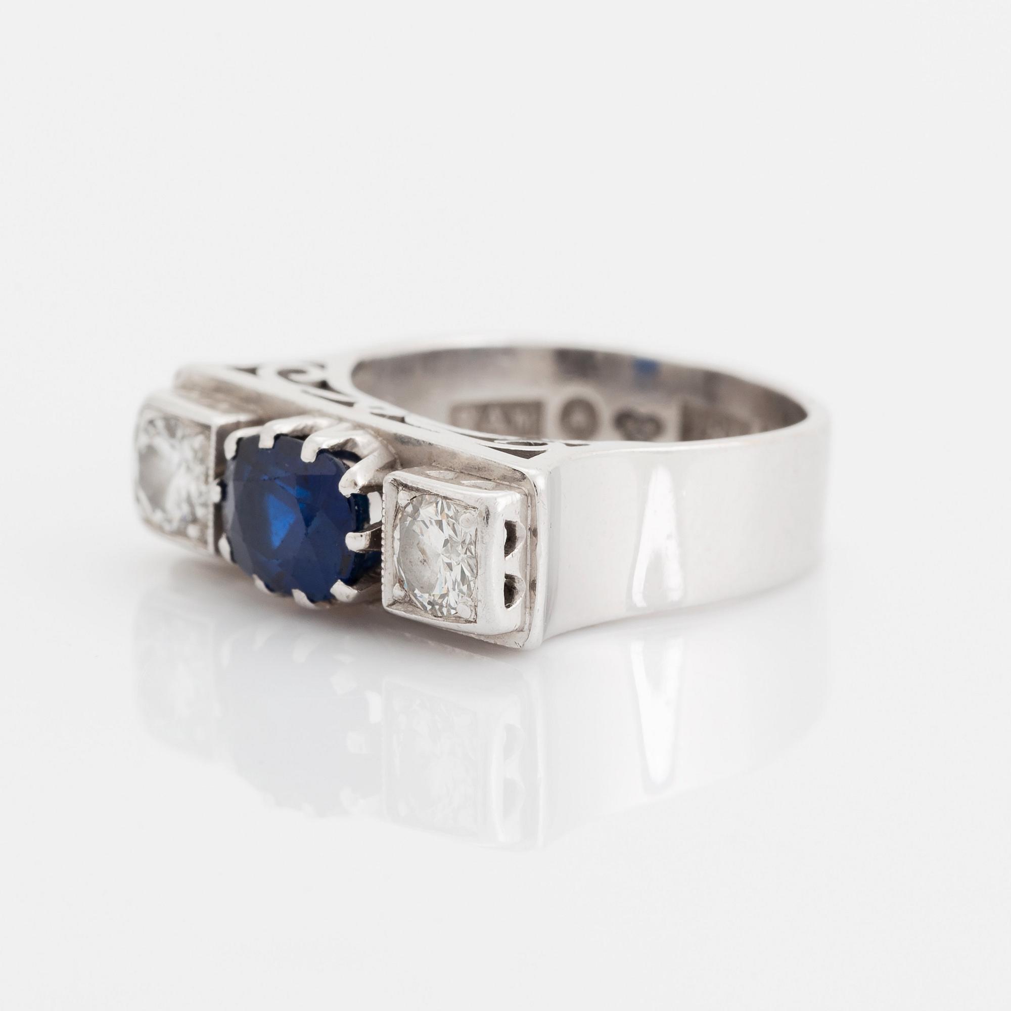 An 18K white gold ring set with a faceted sapphire, possibly synthetic, and round brilliant-cut diamonds.