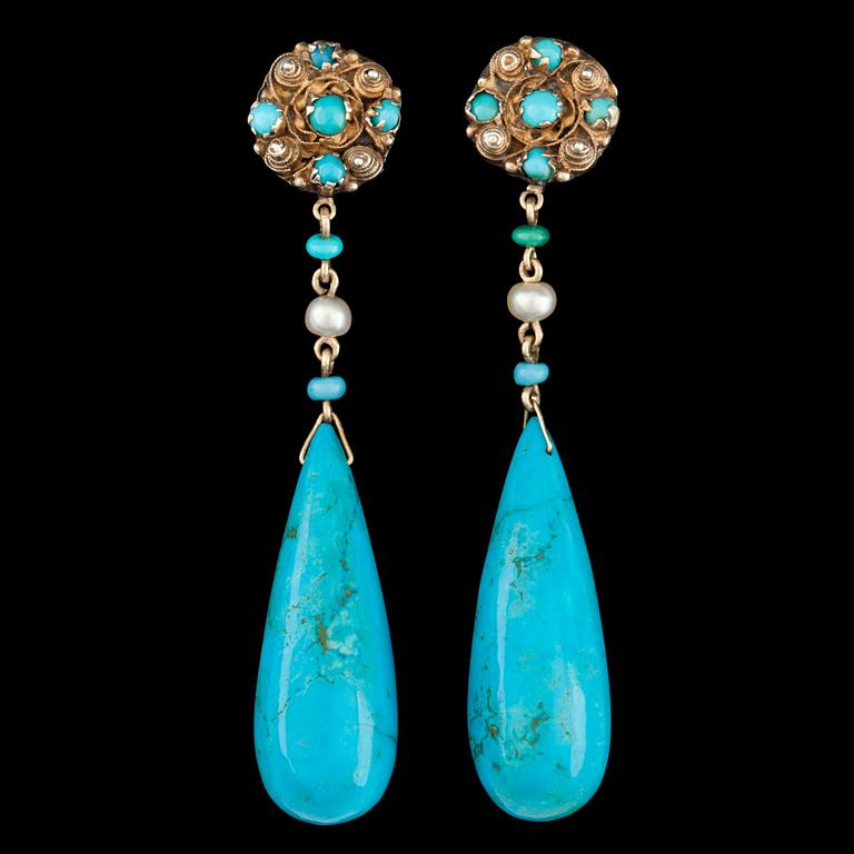 A pair of drop shaped turqouise earrings.