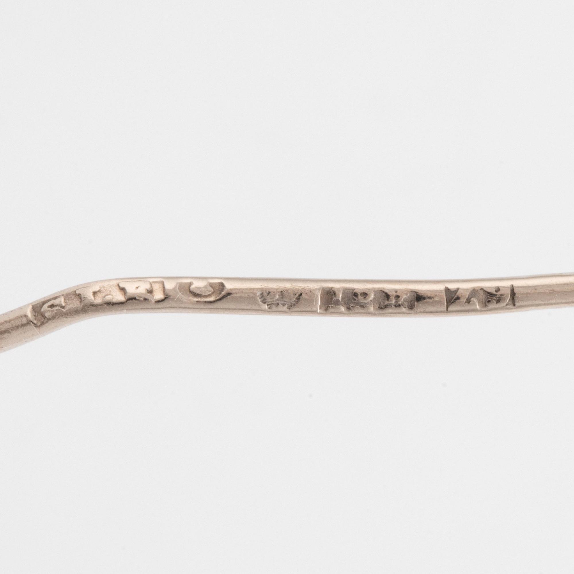 An 18K white gold brooch set with round brilliant-cut diamonds.