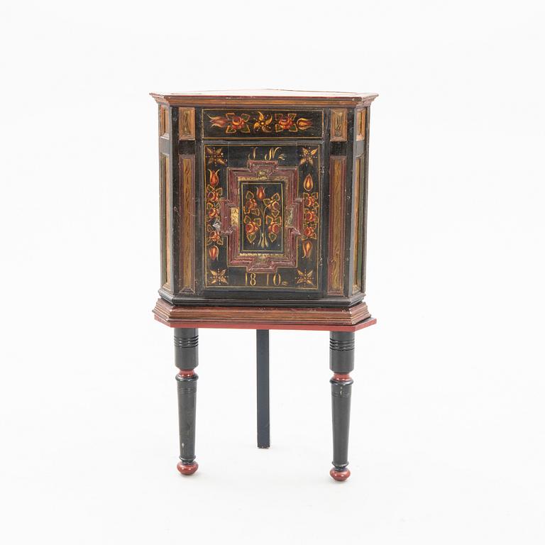 Corner cabinet on a legged stand dated 1810.