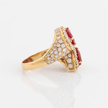 An 18K gold ring set with two facted rubies and round brilliant-cut diamonds.