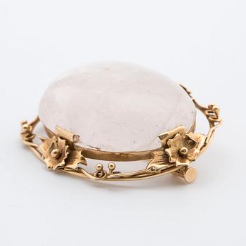 A cabochon-cut rose quartz brooch.