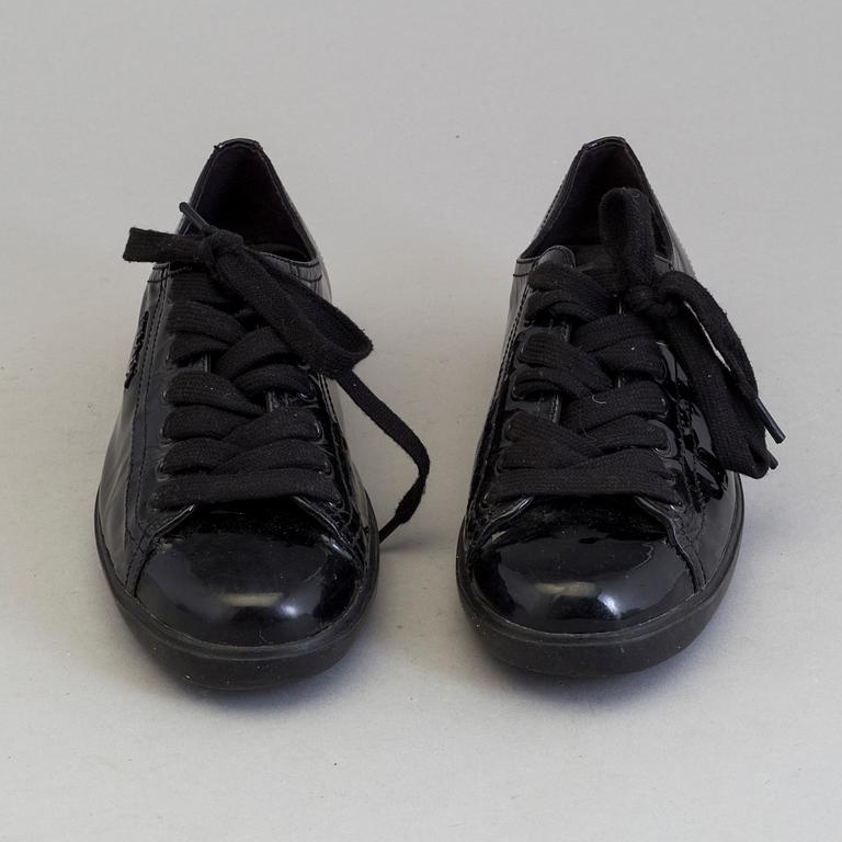 A pair of PRADA black patent leather sneakers.