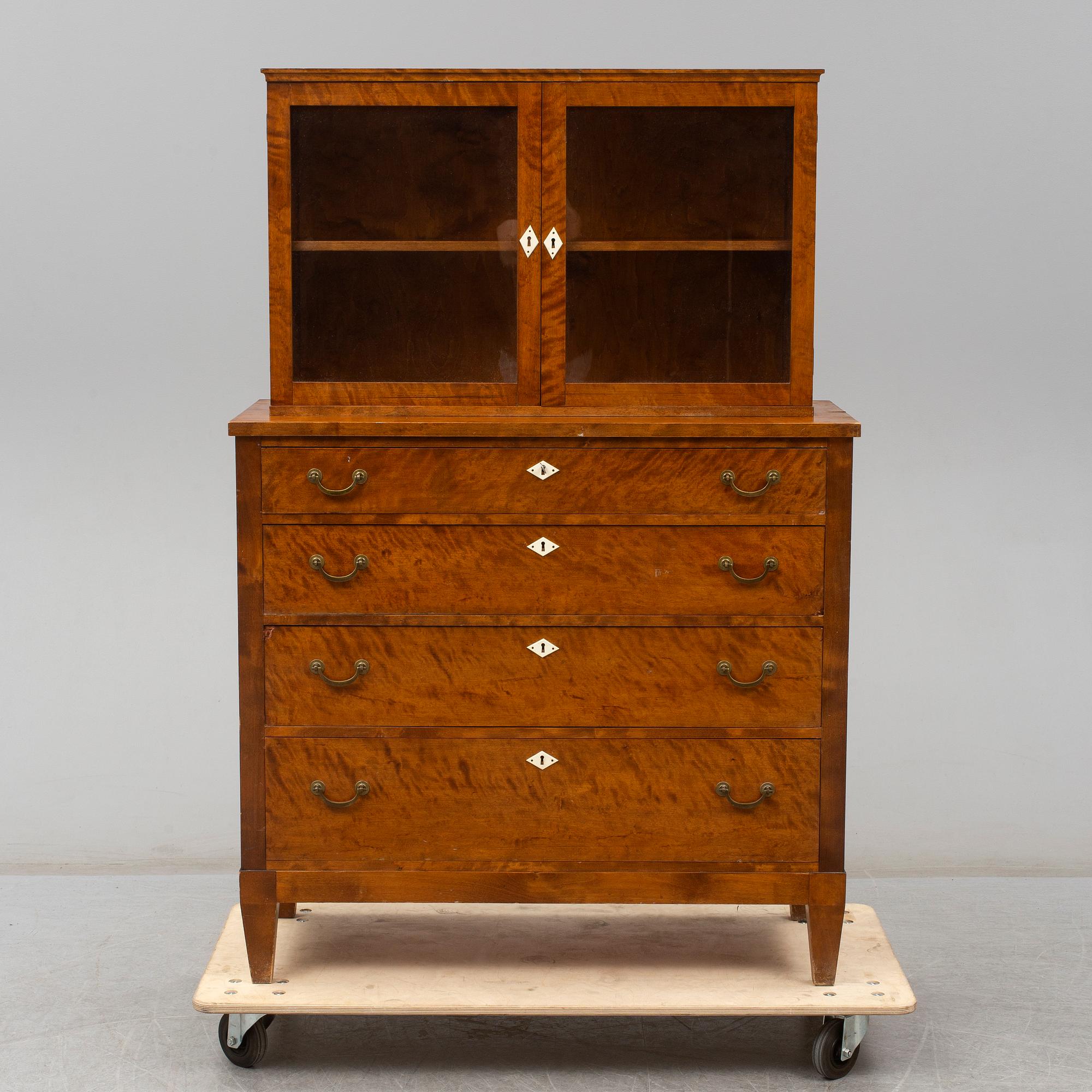 a chest of drawers with a vitrine cabinet from the early 20th century.