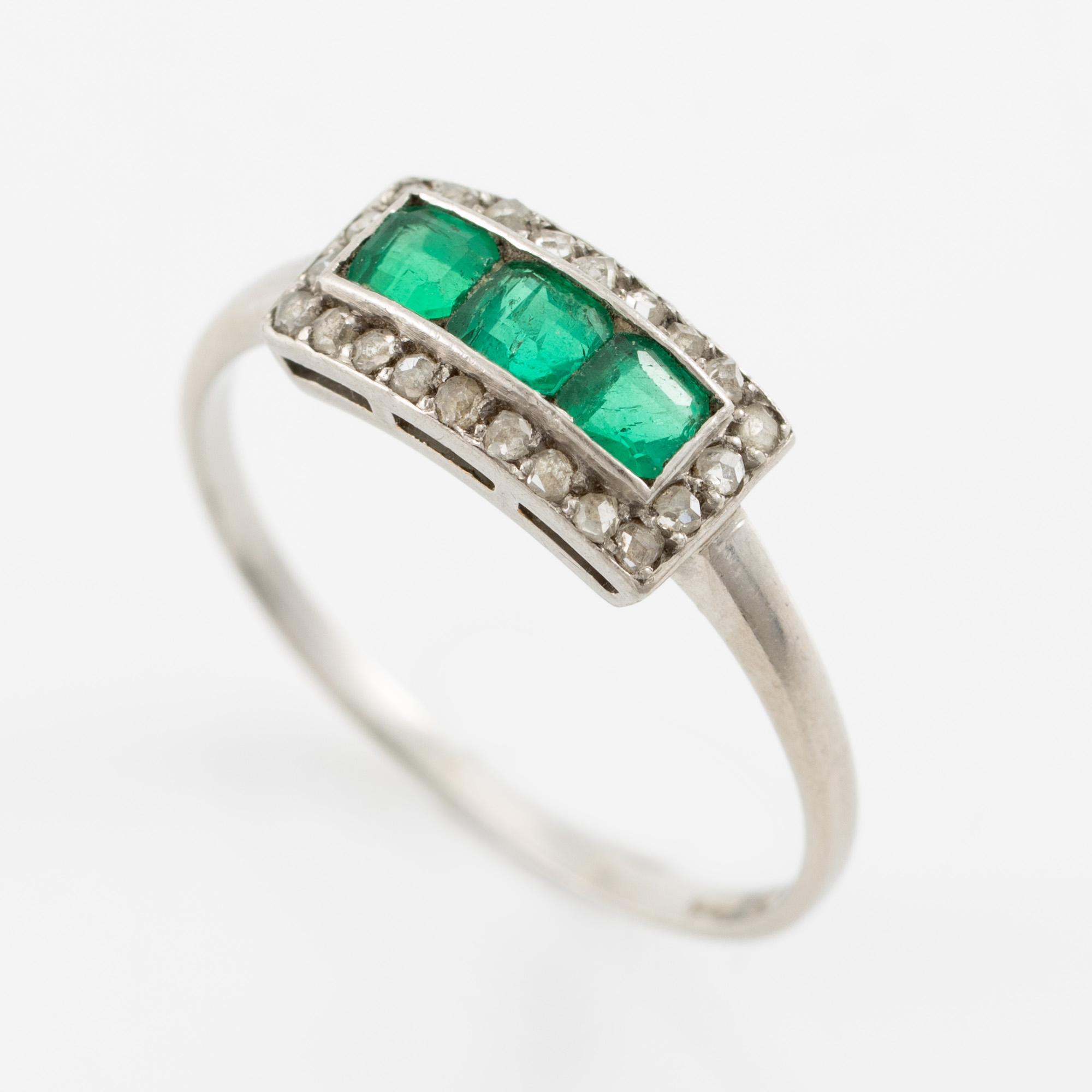 Ring in platinum set with step-cut emeralds and rose-cut diamonds.