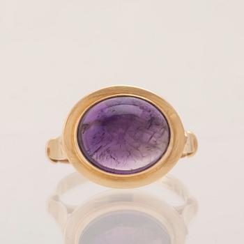 An 18K gold ring set with a cabochon-cut amethyst.