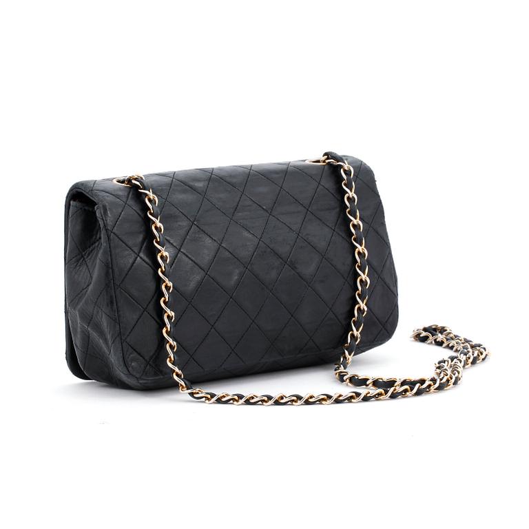 CHANEL, a black leather quilted purse with shoulder strap.