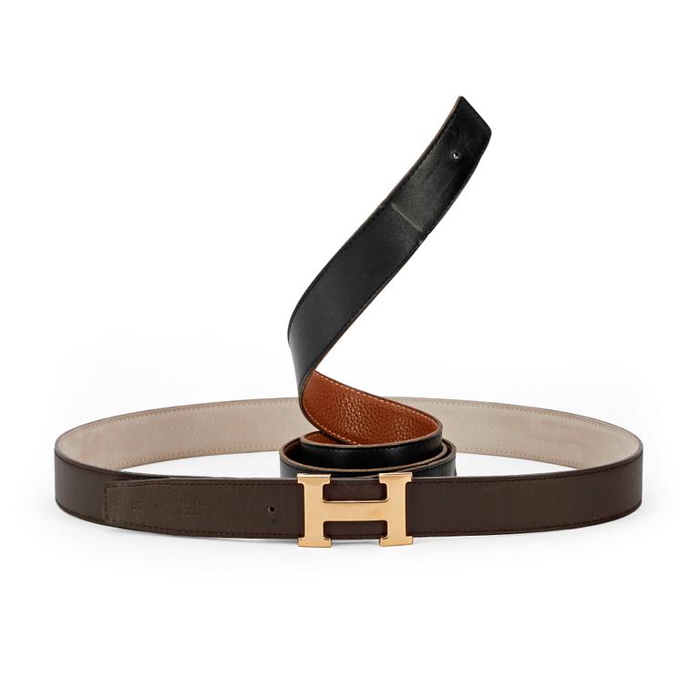 HERMÈS, two pairs of reversible belts, black and brown and brown and white leather with gold colored H belt buckle.