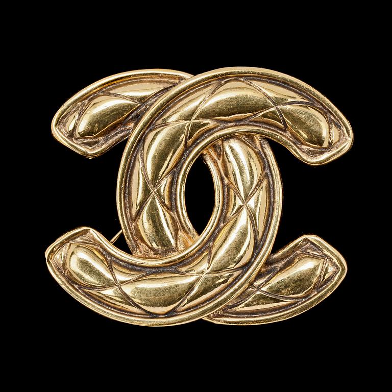 A golden metal brooch by Chanel.