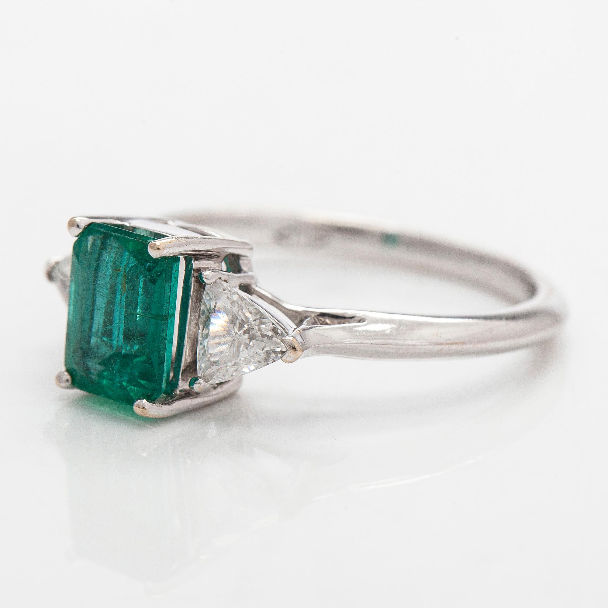 An 18K white gold ring, set with a Zambian emerald and trillion-cut diamonds.