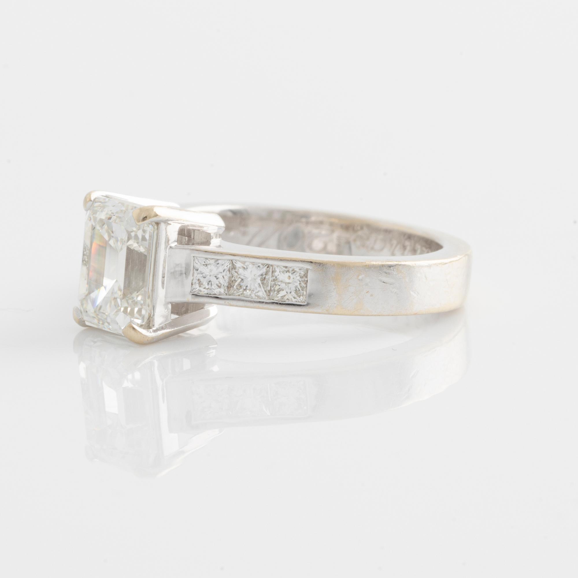 An 18K white gold ring set with an emerald-cut diamond.