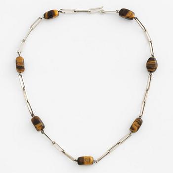 Birger Haglund, a silver and tiger's eye necklace.