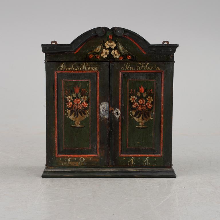 A hanging folk art wall cabinet southern Sweden dated 1844.