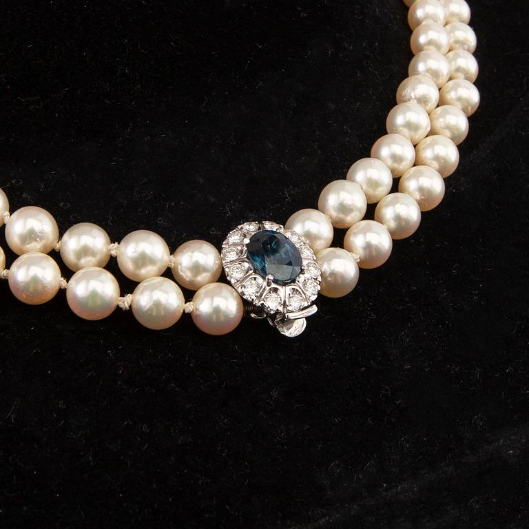 Necklace of cultured pearls with an 18K white gold clasp featuring an oval faceted sapphire and round brilliant-cut diamonds.