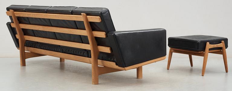 A Hans J Wegner oak and black leather four-seated sofa and stool, Getama, Denmark 1960's.