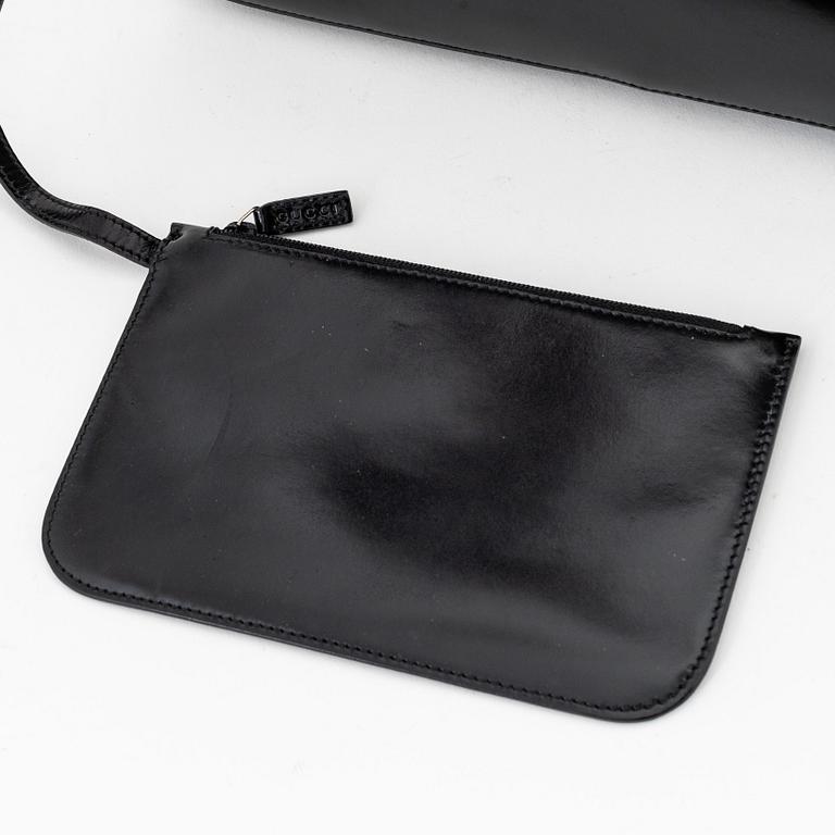 Gucci, a black, patent leather handbag.