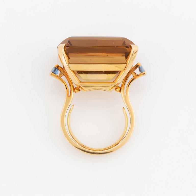 An 18K gold ring set with a faceted citrine and two sapphires.