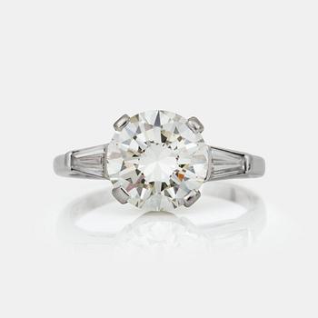 682. A circa 3.00 ct brilliant-cut diamond ring. Center stone flanked by two trapezoid-cut diamonds.