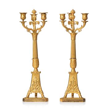 130. A pair of French Empire three-branch ormolu candelabra, early 19th century.