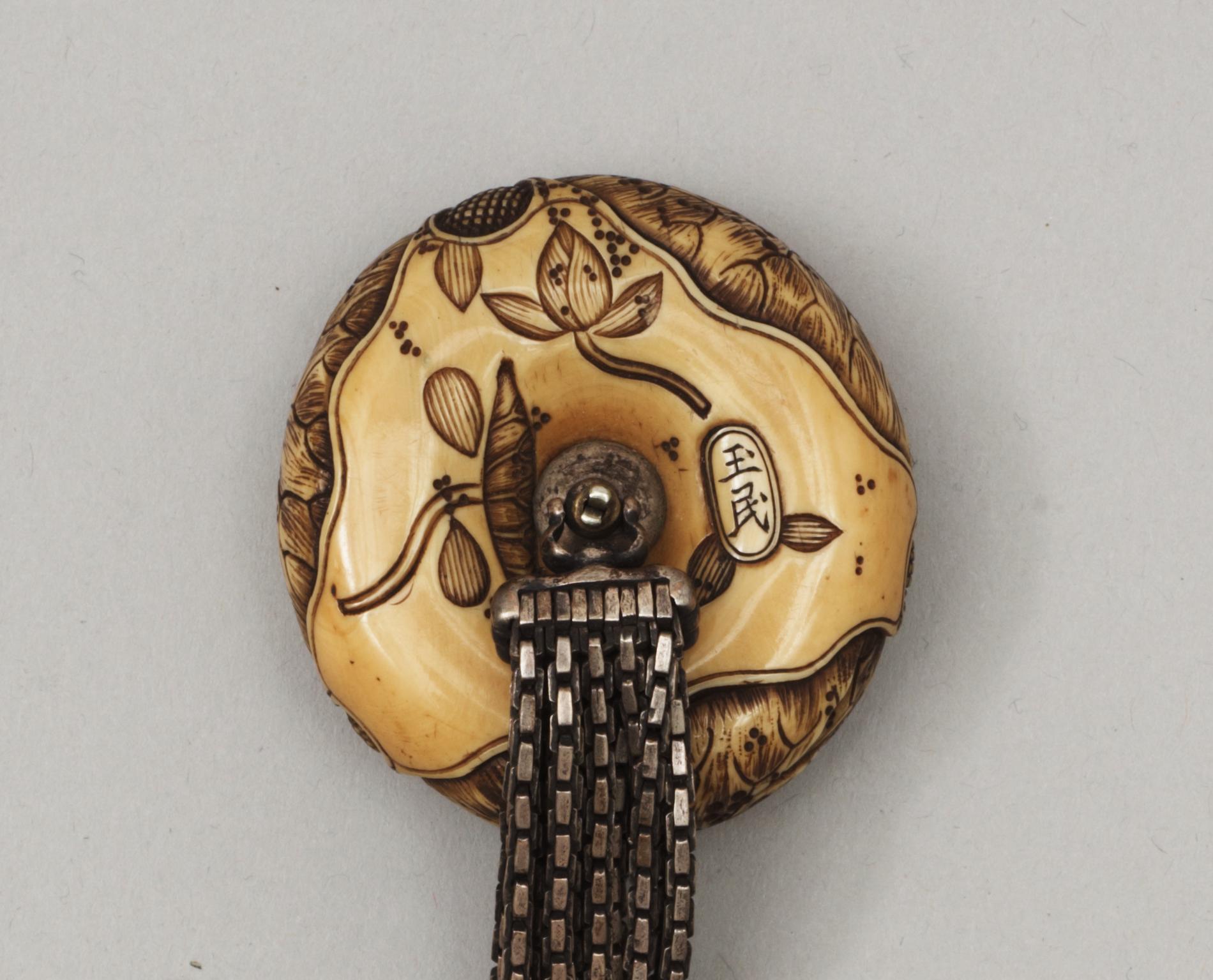 A Japanese embroided tabakoire with a kanamono in the shape of two tigers, a metal chain that holds a carved ivory manjû, second half of 19th Century. Signed.