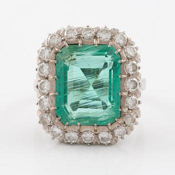 Ring in 18K white gold set with a faceted emerald and round brilliant-cut diamonds.