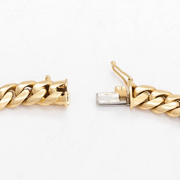 An 18K white/yellow gold curb link bracelet. Foreign marks.