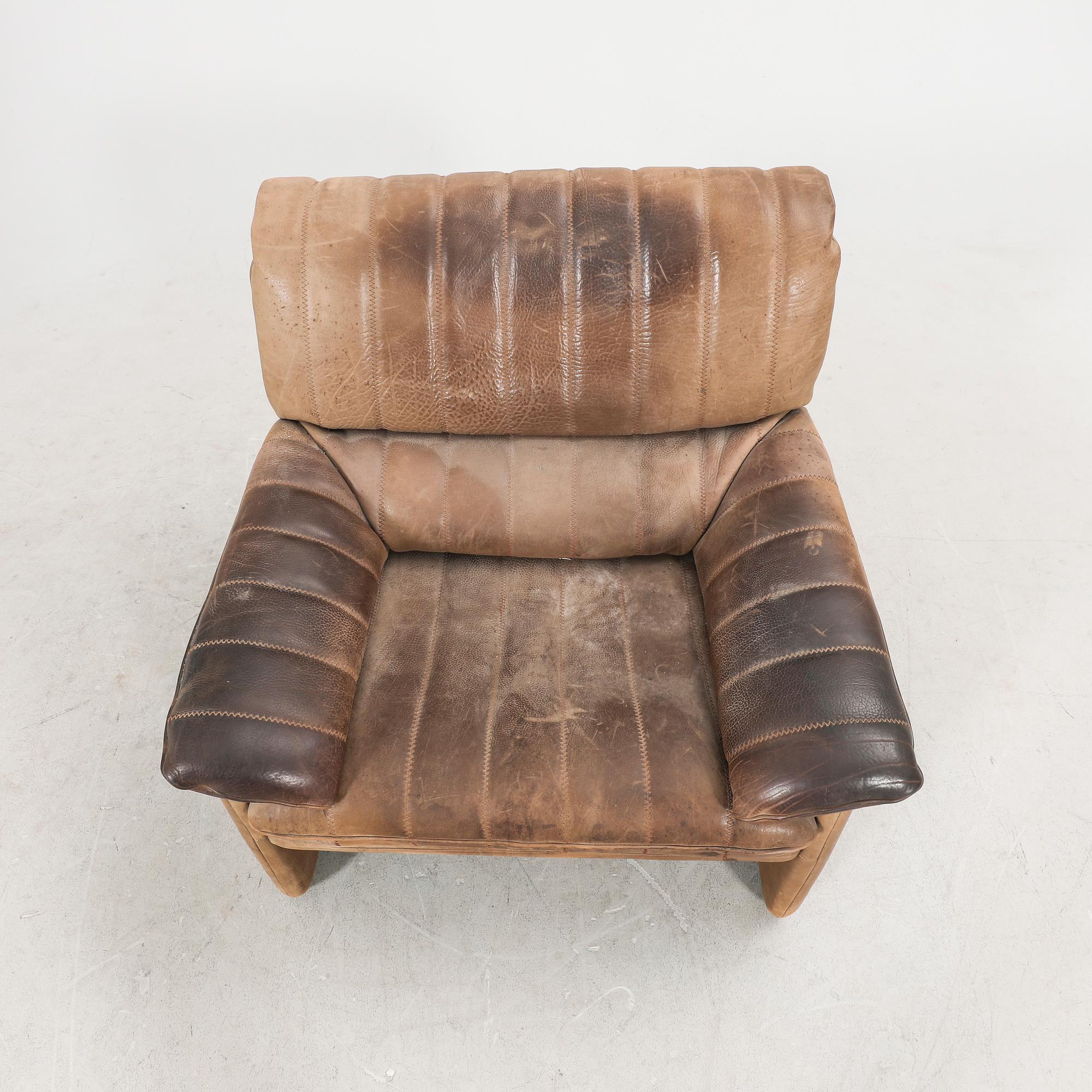 A set of two leather armchairs and a stool by De Sede, Schweiz second half of the 20th century.