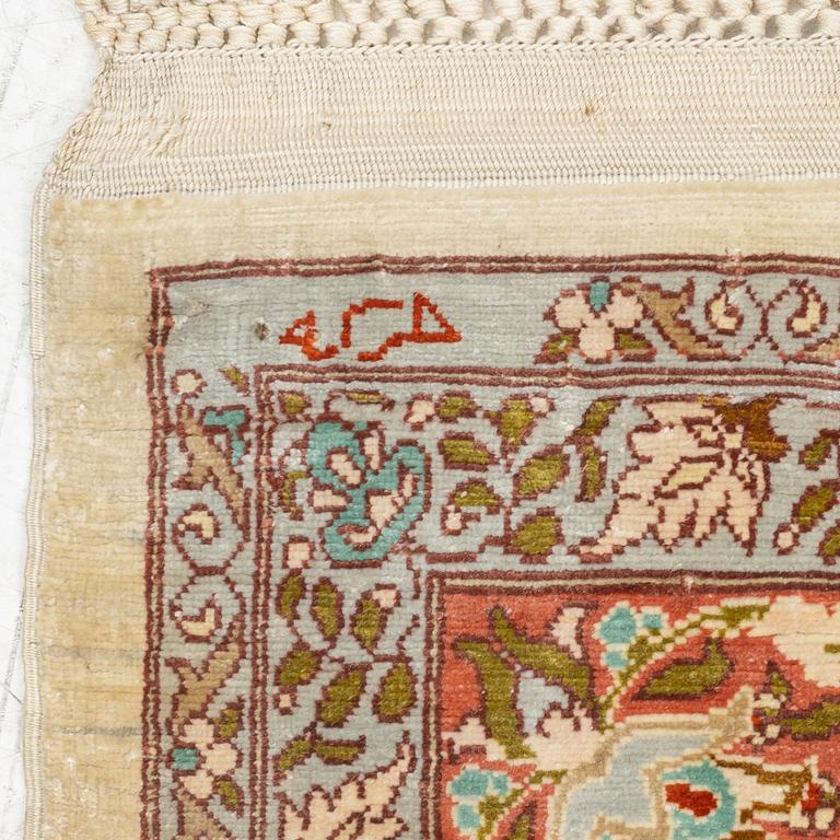 A silk Hereke rug, c. 85 x 55 cm.